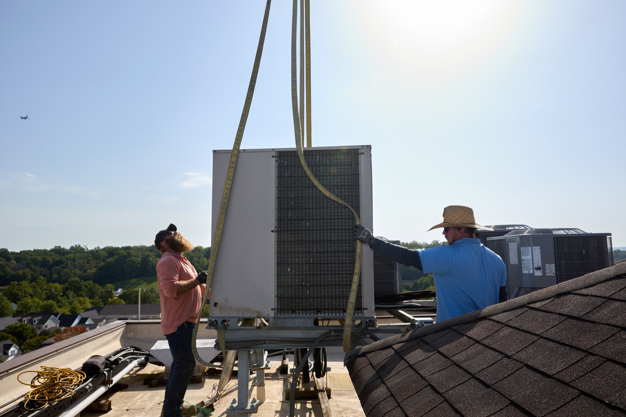 Harpeth Air crew guiding a rooftop HVAC unit into place during a crane lift